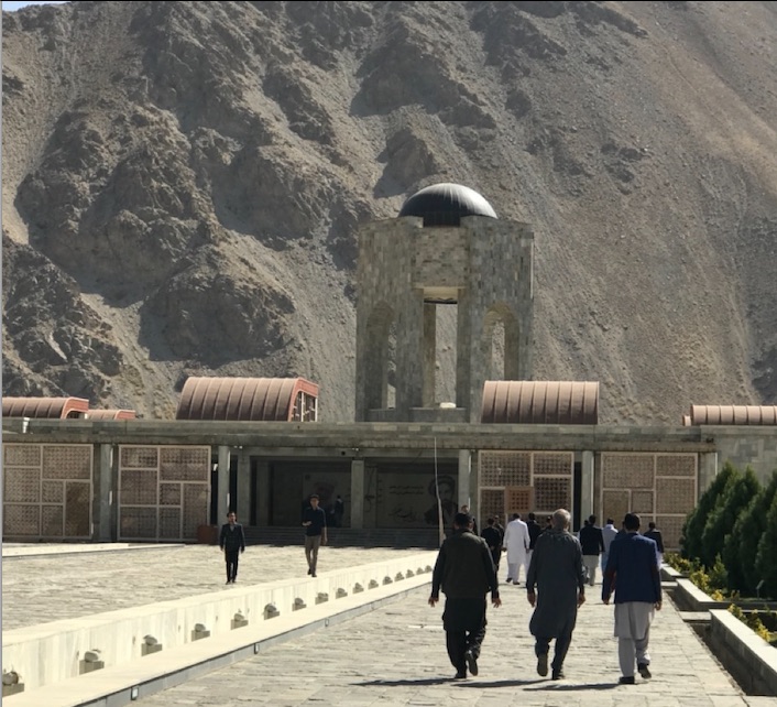 Travelers approaching a cultural site in a mountain setting