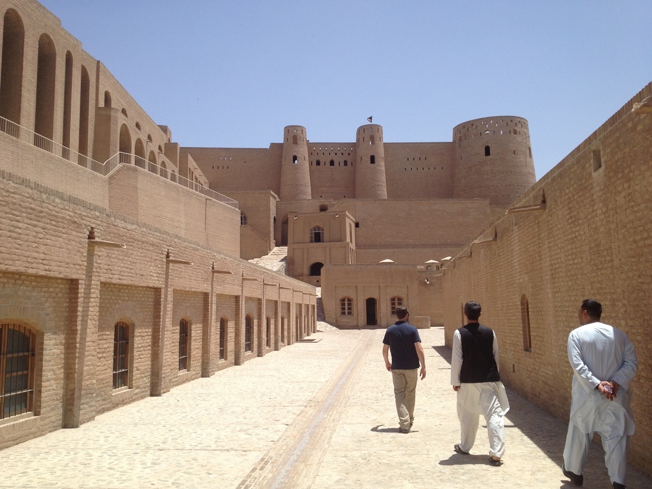 Travelers and local guides walking through a historic citadel complex