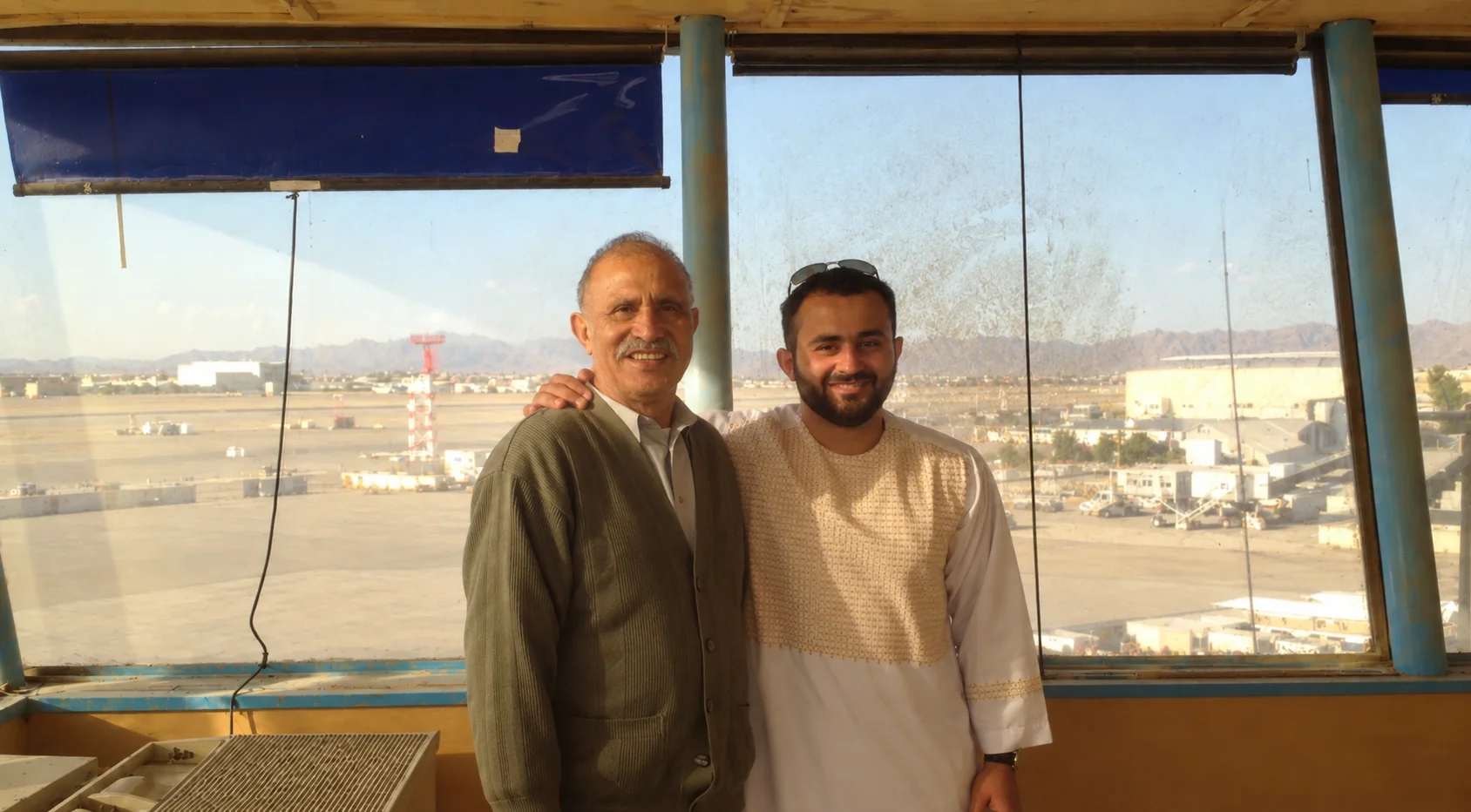 Two travelers at a Kandahar airport overlook with the airfield beyond